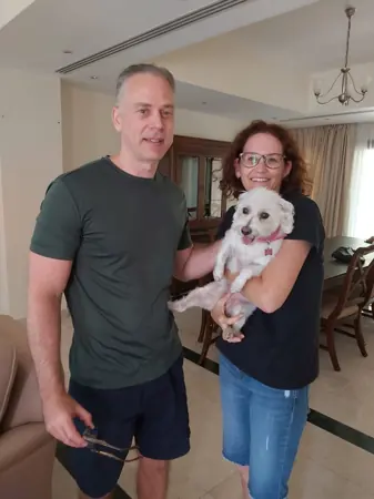 A couple at home with their small white dog.