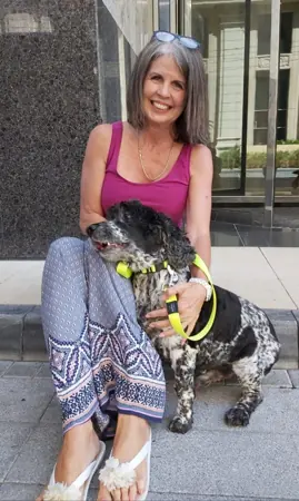 A woman sitting outside with her dog.