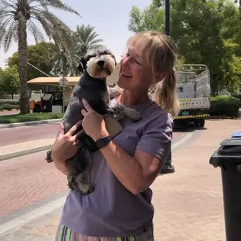 A woman holding her schnauzer outdoors.